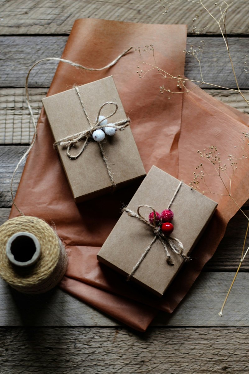 Two small gifts wrapped in kraft paper and tied with twine, on a weathered wooden table