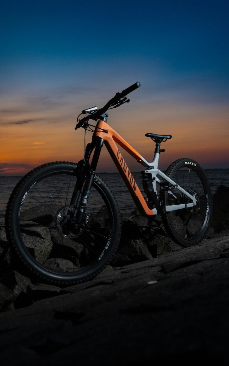 A mountain bike standing on shoreline rocks at dusk